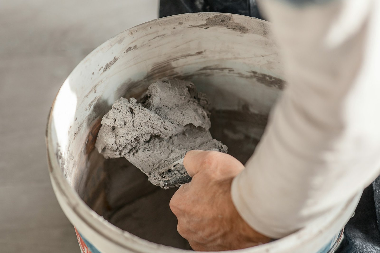 Bucket with construction mix, gypsum plaster, man's hand with a spatula